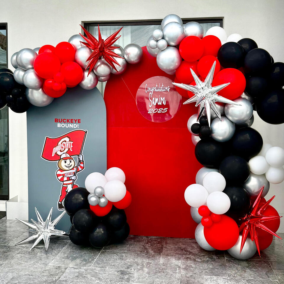 college-inspired grad party set up with arches, organic balloon garland, and custom graphics