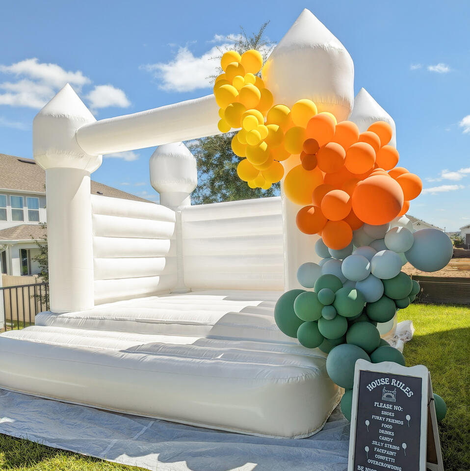white bounce house with organic balloon garland in custom theme