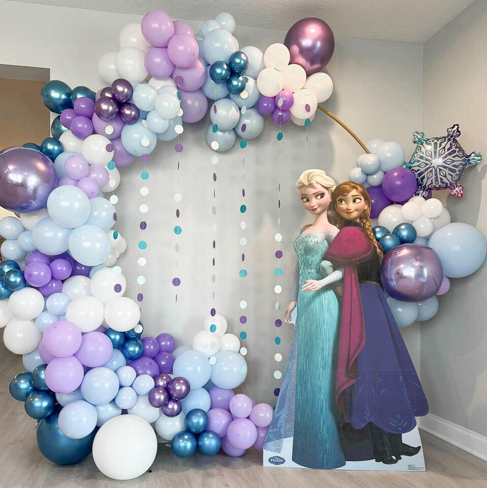 frozen themed balloon hoop with snow props and an elsa and anna cutout